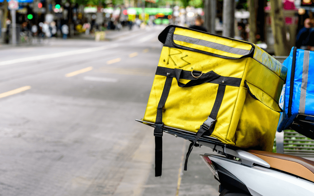 Delivery bike with a large yellow insulated backpack parked on a city street