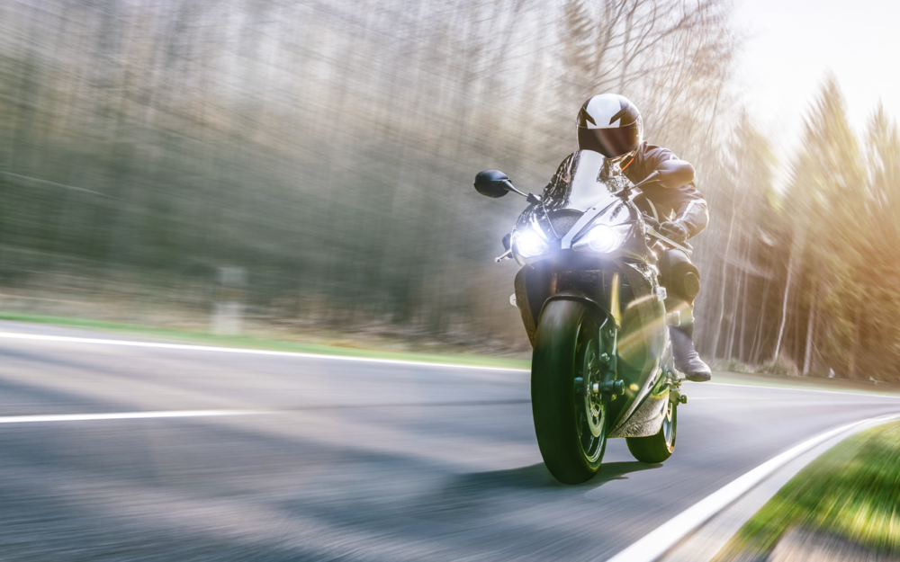 A rider in a white helmet and black leather gear on a sport motorcycle in high speed