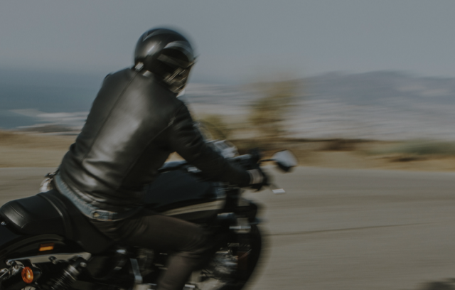 Motorcyclist in black leather riding swiftly on an open road