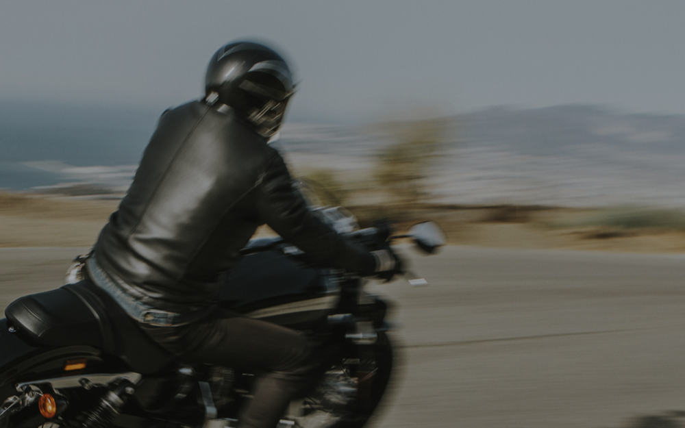 Motorcyclist in black leather riding swiftly on an open road