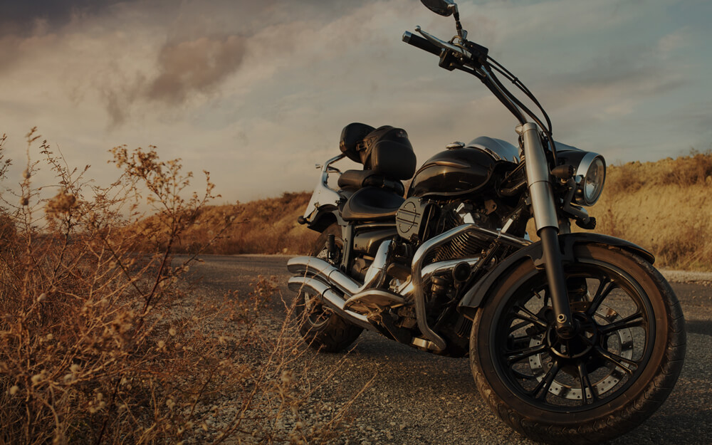 A parked cruiser motorcycle on a deserted road at dusk, with warm sunlight casting soft shadows