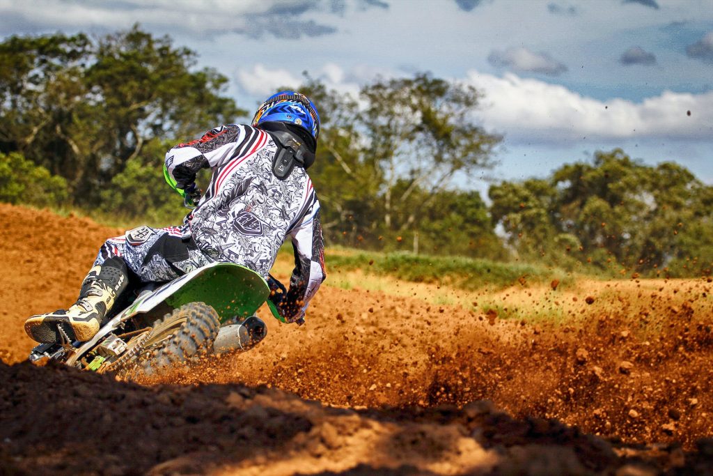 Motocross rider in action on a dirt track, performing a sharp turn with dirt flying