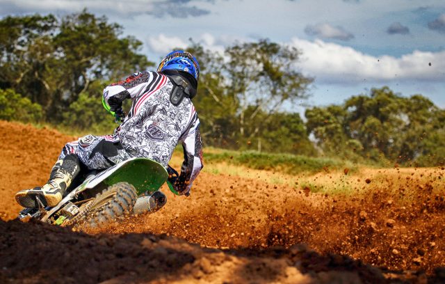 Motocross rider in action on a dirt track, performing a sharp turn with dirt flying