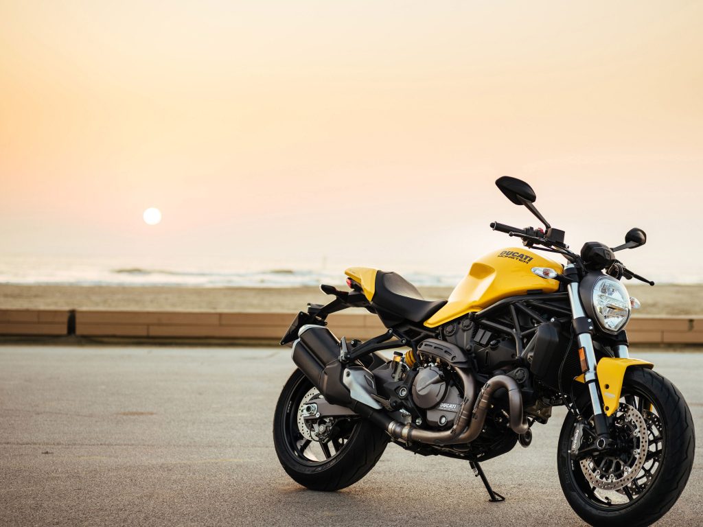 Yellow Ducati motorcycle parked by the seaside at sunset