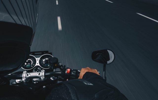 A motorcyclist riding at high speed on an open road, wearing a black helmet
